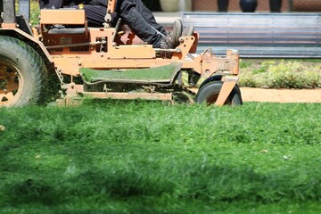 A landscape company cutting long green grass in a park-like area of a residential, commercial area of a suburban part of the Dallas Metroplex. 