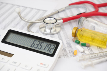 Calculator with numbers on display and stethoscope with medical drugs and vaccines on financial documents.