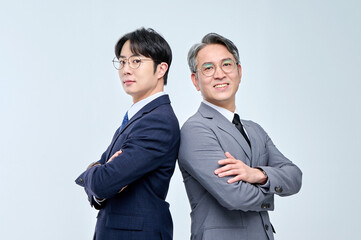 A young office worker man wearing a suit and glasses and a middle-aged man are posing with a variety of confident expressions together.