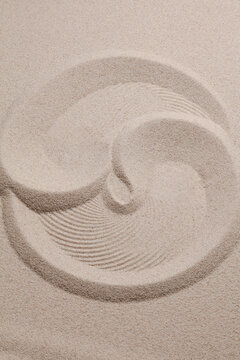 Yin Yang on the sand. Yin and Yang symbol of dualism in ancient Chinese philosophy. Prints on beige sand.