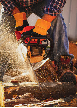 Chainsaw in action cutting wood. Man cutting wood with saw, dust and movements. Chainsaw. Close-up of woodcutter sawing chain saw in motion, sawdust fly to sides.