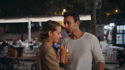 Joyful couple drinking cocktail in evening park closeup. Happy partners dating