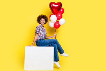 Full length photo of funky sweet woman wear print shirt sitting cube holding balloons bunch empty...
