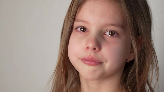 Sad crying little girl looking at camera with tear drops on her eyes