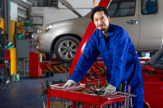 A young professional man technician with car fixing tool standing in garage service station