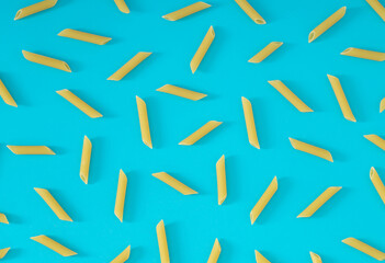Trendy food pattern made of pasta penne rigate on bright blue background. Minimal food concept. Creative pasta pattern background. Flat lay, top of view.
