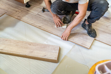 Laminate master man laying wooden laminate parquet on the floor. Home renovation with ceramic...
