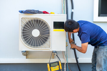 Male technician installing outdoor unit of air conditioner  to cool the household in the summer....