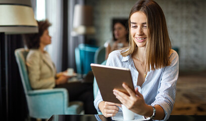 Young happy successful business woman working with tablet in corporate office