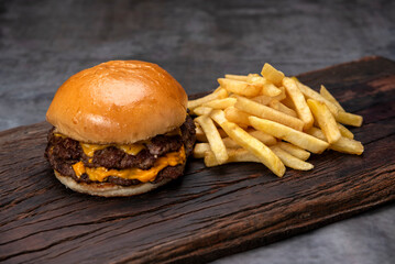 variety of homemade beef burgers with onion cucumber dressings tomato chedar cheese lettuce mayonnaise mustard ketchup barbecue with potato bun and french fries on wooden board