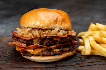 variety of homemade beef burgers with onion cucumber dressings tomato chedar cheese lettuce mayonnaise mustard ketchup barbecue with potato bun and french fries on wooden board