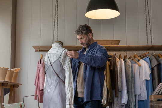 Small business owner preparing mannequin in a vintage clothing store