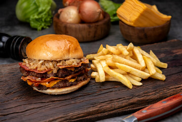 variety of homemade beef burgers with onion cucumber dressings tomato chedar cheese lettuce mayonnaise mustard ketchup barbecue with potato bun and french fries on wooden board