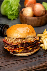 variety of homemade beef burgers with onion cucumber dressings tomato chedar cheese lettuce mayonnaise mustard ketchup barbecue with potato bun and french fries on wooden board