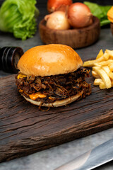 variety of homemade beef burgers with onion cucumber dressings tomato chedar cheese lettuce mayonnaise mustard ketchup barbecue with potato bun and french fries on wooden board