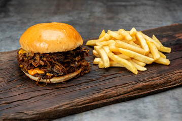 variety of homemade beef burgers with onion cucumber dressings tomato chedar cheese lettuce mayonnaise mustard ketchup barbecue with potato bun and french fries on wooden board