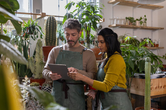 Plant shop owners using a digital tablet in store for electronic banking