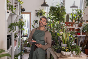 Plant shop owner using a digital tablet in store for customer orders