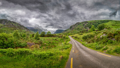 Landscape and Cloudy Sky along Gap of Dunloe - Road Winding Through Lush Green Valley