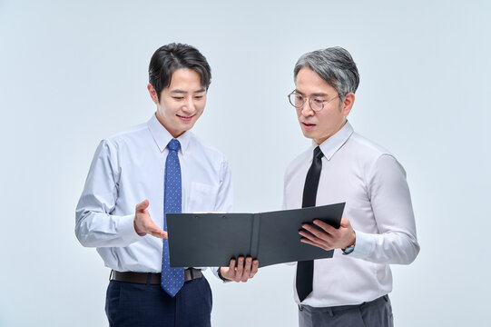 A middle-aged office worker man in a suit and glasses are holding a document file together and discussing with various confident expressions and poses.