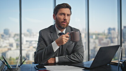 Calm businessman sipping coffee thinking solution. Inspired manager type laptop