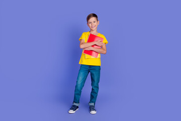 Photo of smiling cheerful cute clever smart elementary school boy wear stylish clothes hold books isolated on violet color background