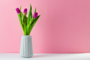 boquet of tulip on a peach color background standing in a vase