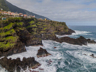Aerial view of Seixal, a little village by the ocean with waves and surrounded with incredible mountains on the island of Madeira, Portugal.