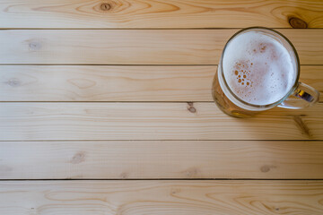 A mug of beer sits on a wooden table.