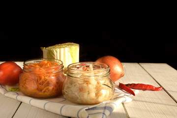 Fermented preserved vegetarian food concept. Probiotics food. Korean carrot, marinated sauerkraut glass jars over kitchen table.