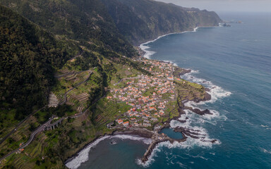 Aerial view of Seixal, a little village by the ocean with waves and surrounded with incredible mountains on the island of Madeira, Portugal.