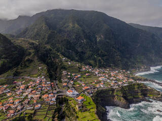 Aerial view of Seixal, a little village by the ocean with waves and surrounded with incredible mountains on the island of Madeira, Portugal.