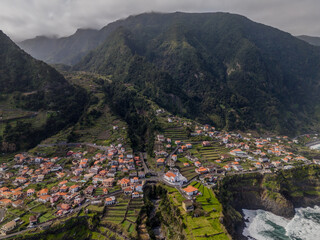Aerial view of Seixal, a little village by the ocean with waves and surrounded with incredible mountains on the island of Madeira, Portugal.