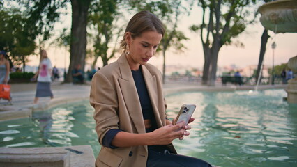 Joyful woman taking selfie video in city park. Beautiful urban girl calling cell