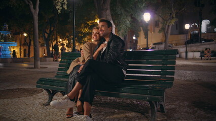 Affectionate couple sitting park cuddling in evening date. Happy spouses resting