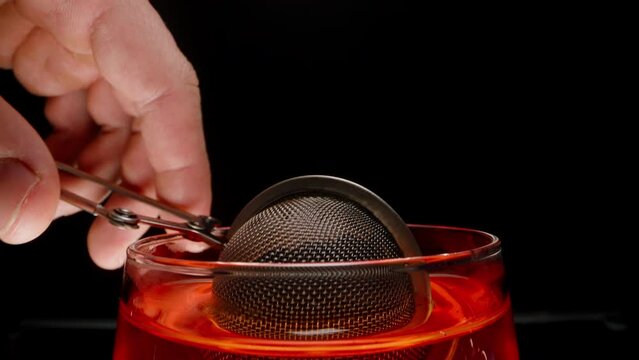 A metal sieve that opens up, and inside are tea leaves for personal steeping in the glass.
