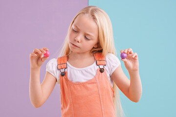 Studio, girl and decision with candy, dessert and choice for snack and childhood. Child, gumball and yummy selection for tasty, eating and choosing on vibrant split pastel pink and blue background