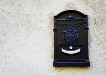 Black special mailbox on a white house wall in Italy