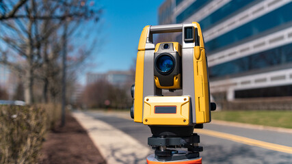 land surveying total station instrument on a tripod with a building in the background
