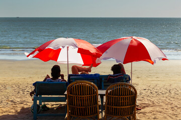 Vacationers under colorful umbrellas on the ocean shore - 764096885