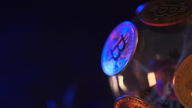 Close up BTC Bitcoin coin on sphere with blue neon lights rotating on dark background close up, cyberspace. Finance asset. World in cryptocurrency money.