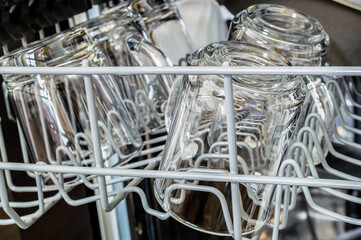 A dishwasher is full of glassware, including cups and mugs. The glassware is being washed and dried