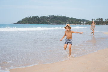 Fototapeta premium Beautiful young mother and son run at beach in sunny day and hugging