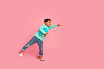 Fototapeta na wymiar Full length photo of adorable little boy hold book fly superman dressed stylish cyan garment isolated on pink color background