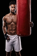 Fototapeta na wymiar Portrait, body and fitness man with punching bag in studio for training, challenge or power performance on black background. Face, chest and male fighter at gym for wellness, resilience or workout