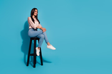 Full length photo of dreamy cheerful woman wear silky blouse sitting stool looking empty space...