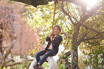 Boy, tyre swing and portrait in garden with happiness, playing and countryside vacation in summer....