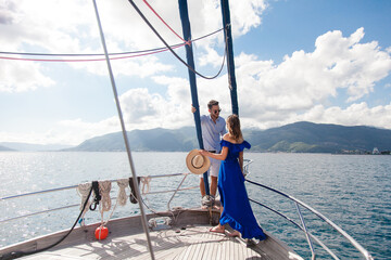 Travel on yacht at sea. Young couple in love sailing on summer vacation. Happy travelers enjoying safe holiday on sailboat. Successful lifestyle. Intimate romantic date with beautiful landscape view.