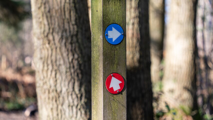 Blue and red arrows way marker sign on a trail
