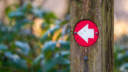Red arrow way marker sign on a trail
